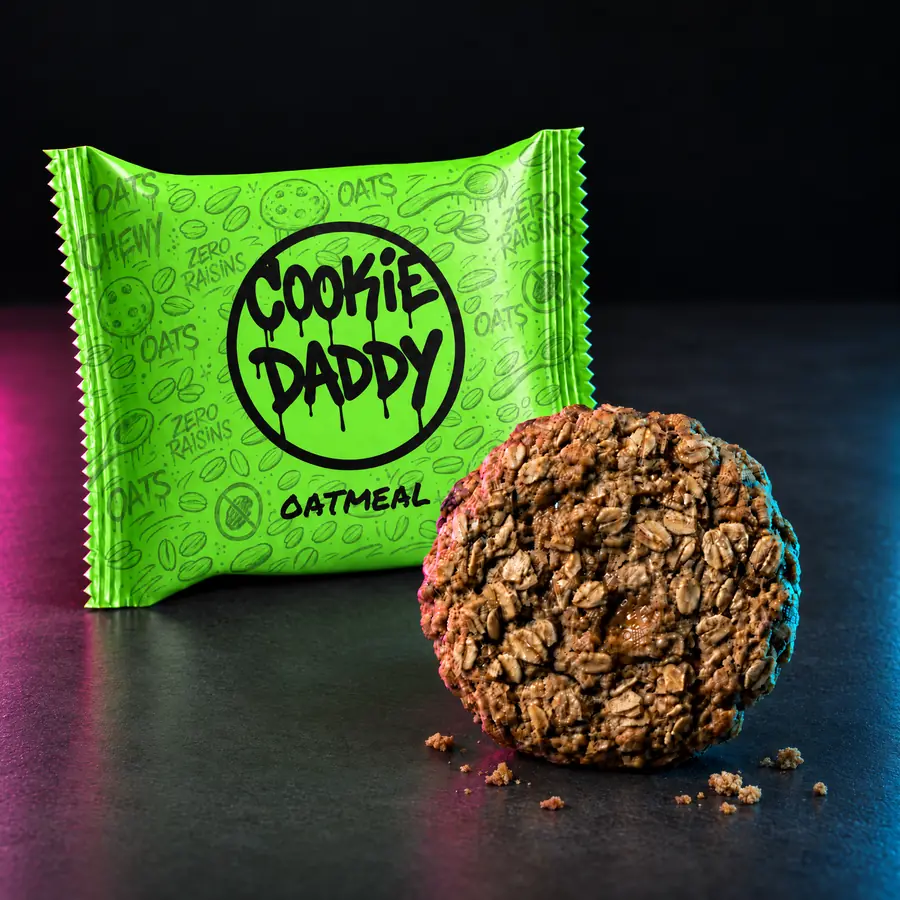 Neon green Cookie Daddy wrapper, black ring tag with OATMEAL printed under it, unwrapped oatmeal cookie in front on dark concrete