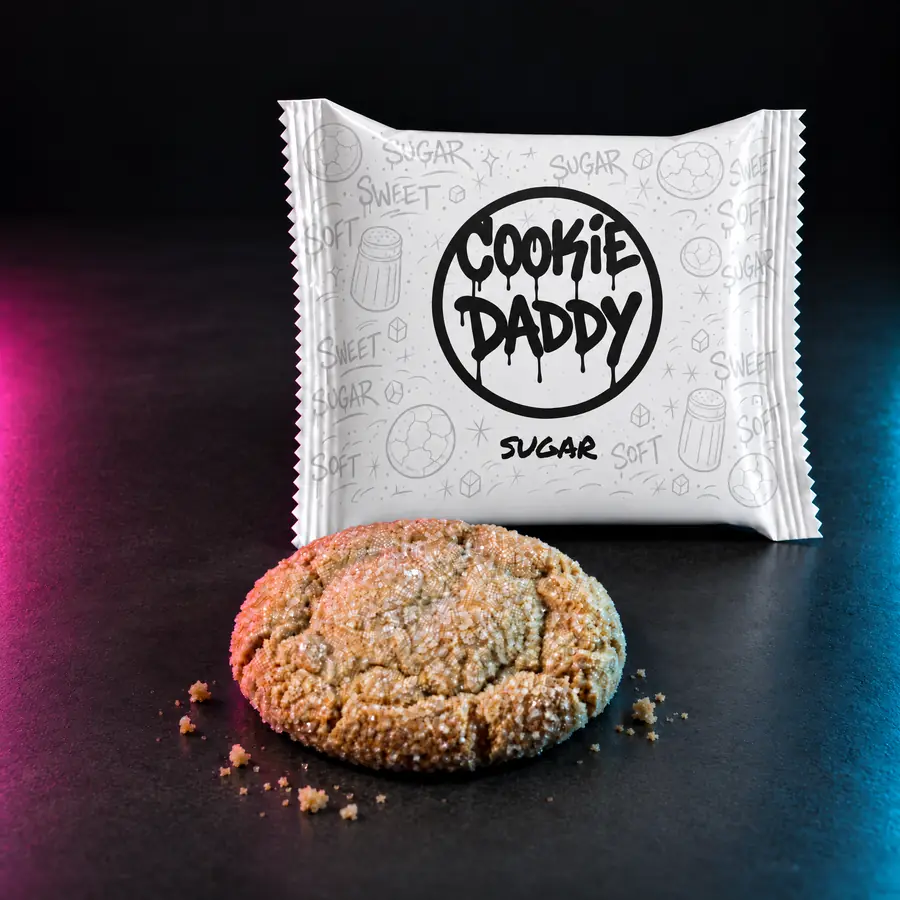White Cookie Daddy wrapper, black ring tag with SUGAR printed under it, unwrapped sugar cookie in front on dark concrete
